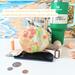 The bottom of an orange and yellow print water bottle bag is displayed with money, cell phone and chap stick. Beside the bag is a Stanley.
